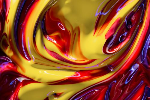 Free A close-up of colorful, swirling paint with vibrant yellow and red hues. Stock Photo