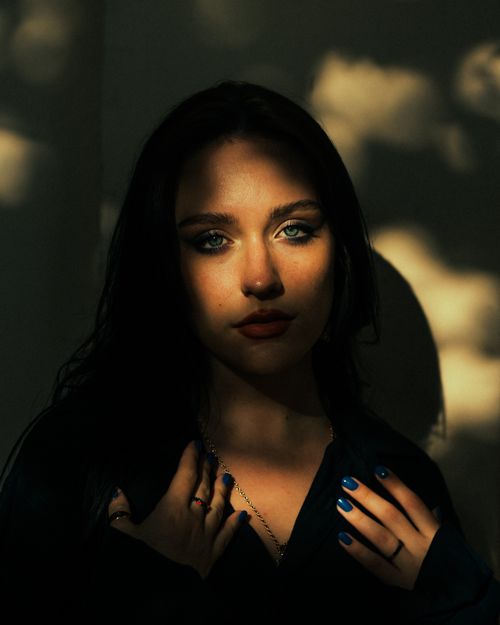 Free Intriguing portrait of a woman in shadows and light, highlighting her blue eyes and silver necklace. Stock Photo