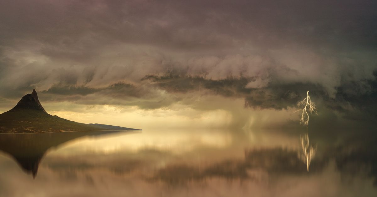 Photo by Johannes Plenio Stunning landscape of a storm over an island with lightning striking the calm water.