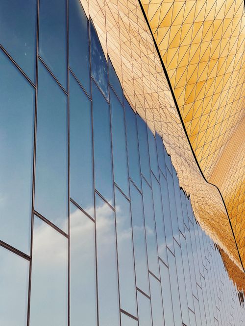 Free Low angle view of a modern building reflecting the sky in its glass facade. Stock Photo