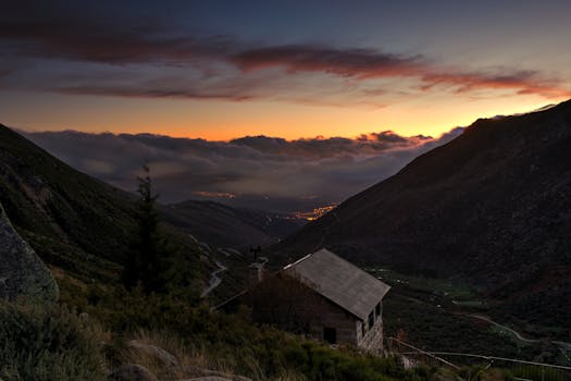 Breathtaking sunset view of a rural mountain landscape with a distant valley and glowing sky.