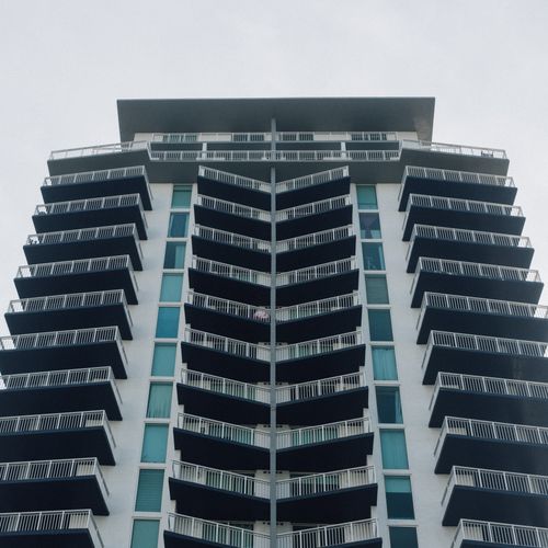 Free Contemporary skyscraper with glass facade and balconies, showcasing urban architectural elegance. Stock Photo