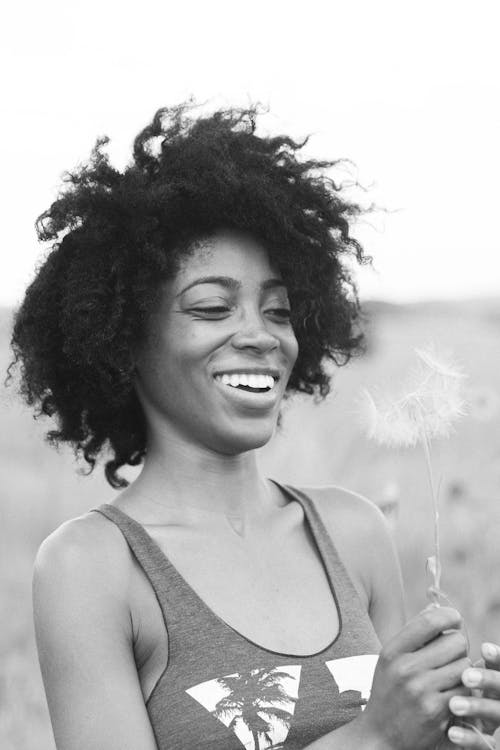 Free A Woman in a Sleeveless Tank Top Holding a Dandelion Stock Photo