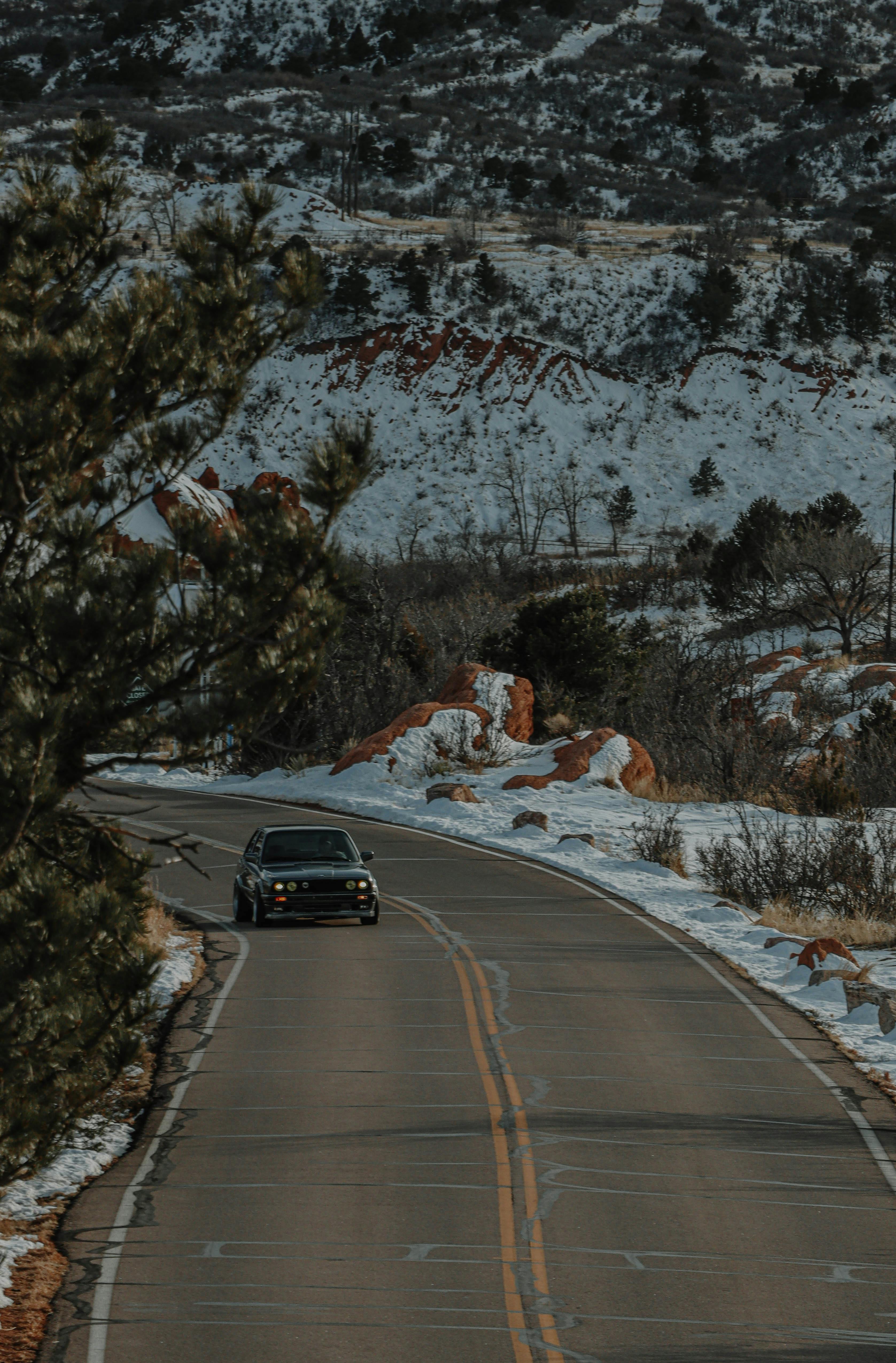 an aerial photography of a moving car on the road near the snow covered mountain