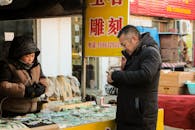 Man in Black Jacket Standing in Front of Food Stall