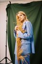 Blond Woman in Blue Suit Cuddling Bunch of Dried Grass