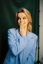 Blond Woman Smiling with Hand on Mouth