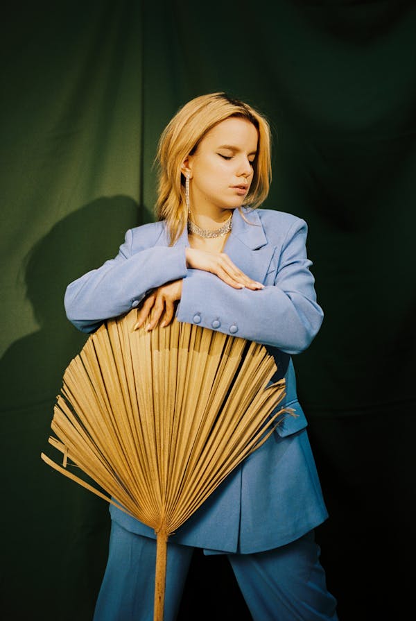 Young Woman Posing in Blue Suit Leaning on Dried Palm Leaf