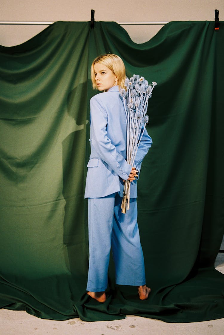 Blond Woman Standing Back With Dried Flowers Behind Her Back