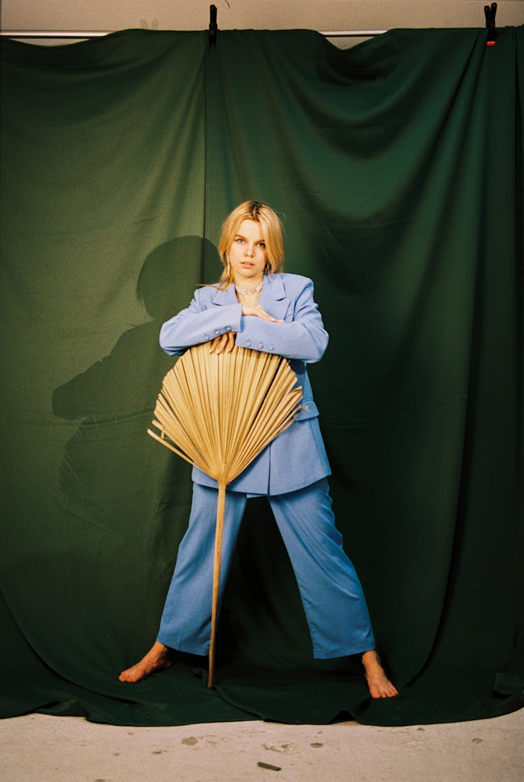 Woman In A Blue Suit Holding A Dried Palm Fan