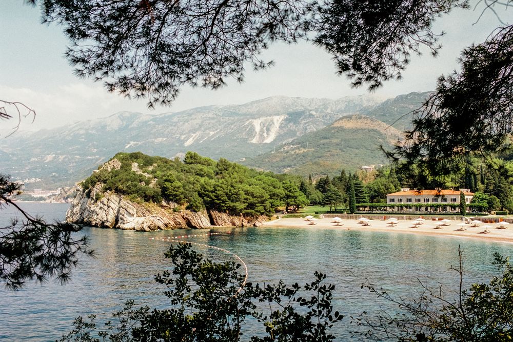 Plajă mărginită de pini și munți verzi în zona Miločer, lângă Sveti Stefan