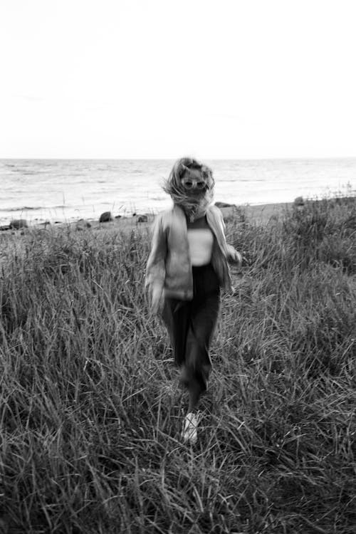 Grayscale Photo of a Person Running on Grass Field