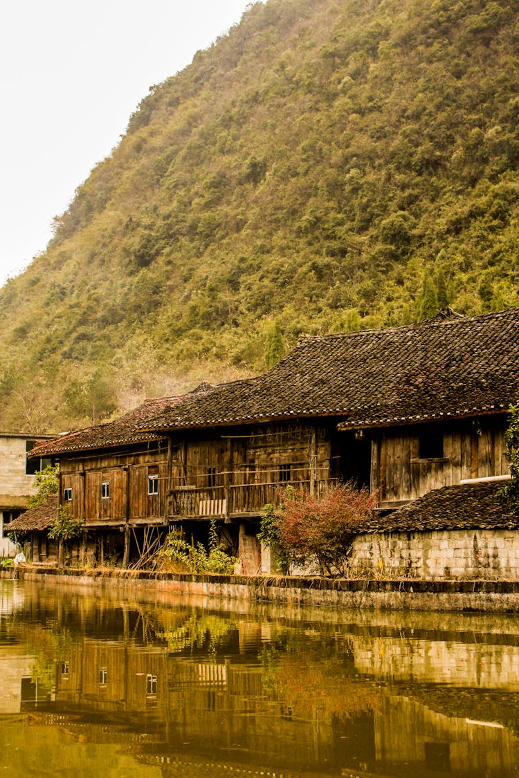 Wooden Houses By Creek Near Mountain In China