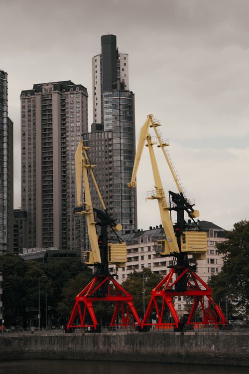 Free High-rise buildings and industrial cranes at a city harbor showcasing urban development. Stock Photo