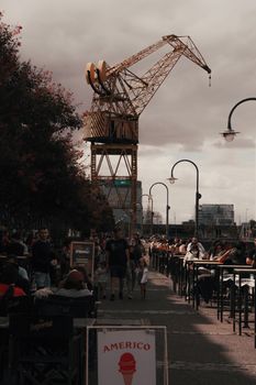 Lively street scene in Puerto Madero with a prominent crane and pedestrians enjoying the day.