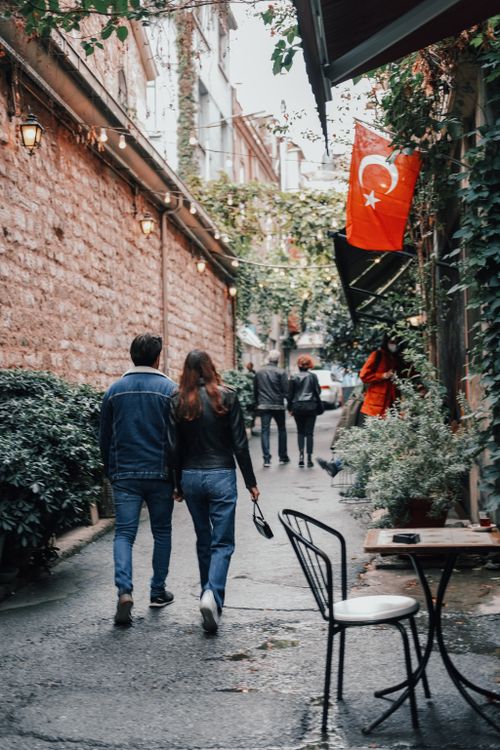 Free Couple strolling through a charming alley in Istanbul, with Turkish flag on display. Stock Photo