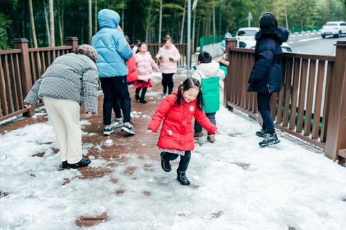 Free Group of children playing on a snowy wooden walkway, wearing winter clothing. Stock Photo
