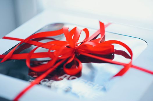 A close-up shot of a sophisticated gift box wrapped with a striking red ribbon bow, perfect for holiday gifting.