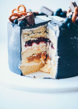 Close-up of a layered cake with berries and pretzels on top, a perfect dessert indulgence.