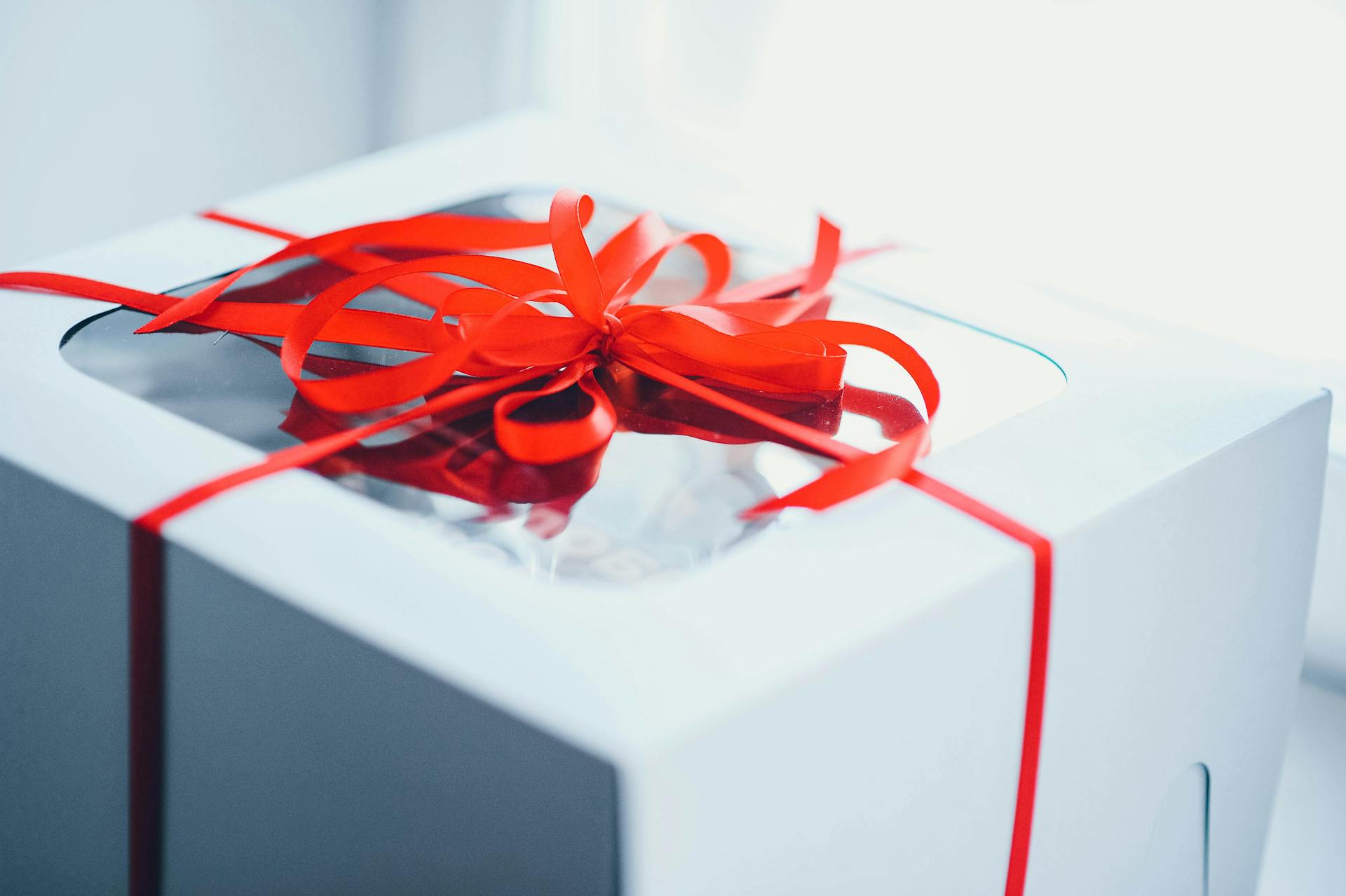 Close-up of a white gift box wrapped with a red ribbon, perfect for celebrations and special occasions.