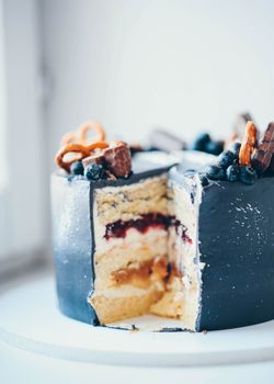 Delicious layered cake topped with blueberries, pretzels, and chocolate bars.