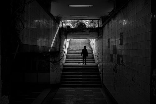 Free A person stands in a dimly lit urban underpass revealing stark contrasts and silhouettes. Stock Photo