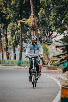 Cyclist wearing helmet and safety gear riding in a park in Jakarta, Indonesia.