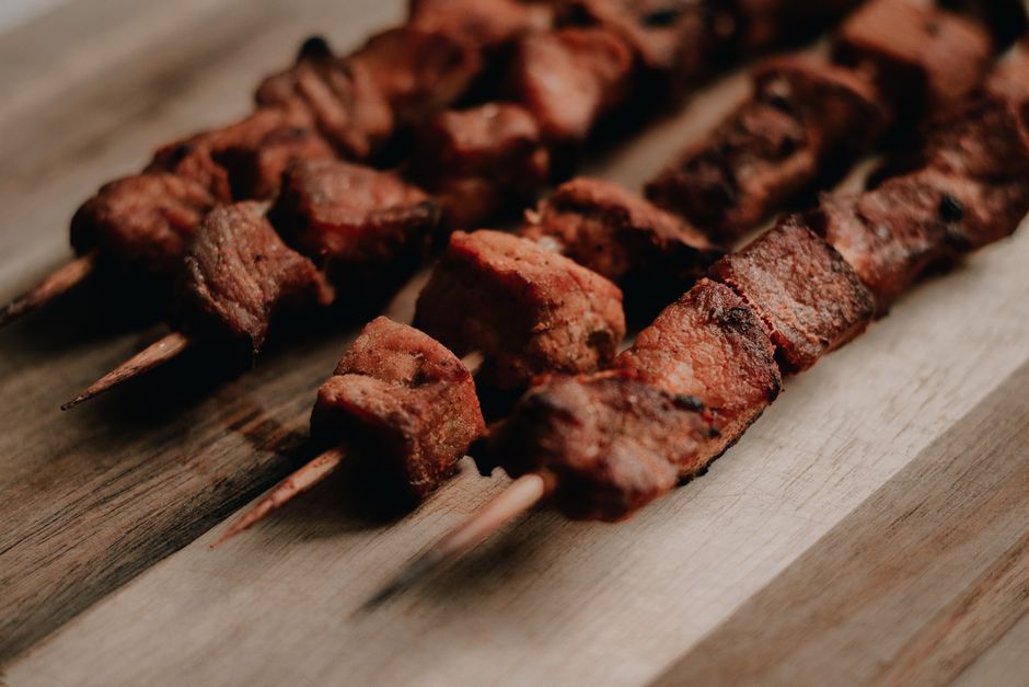 Close-up view of grilled meat skewers on a wooden board, perfect for BBQ-themed visuals.
