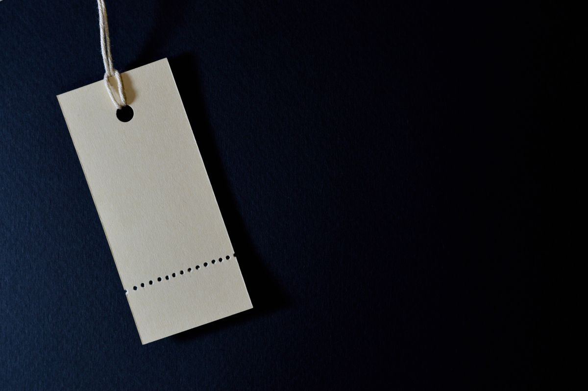 A single blank price tag on a string against a dark background