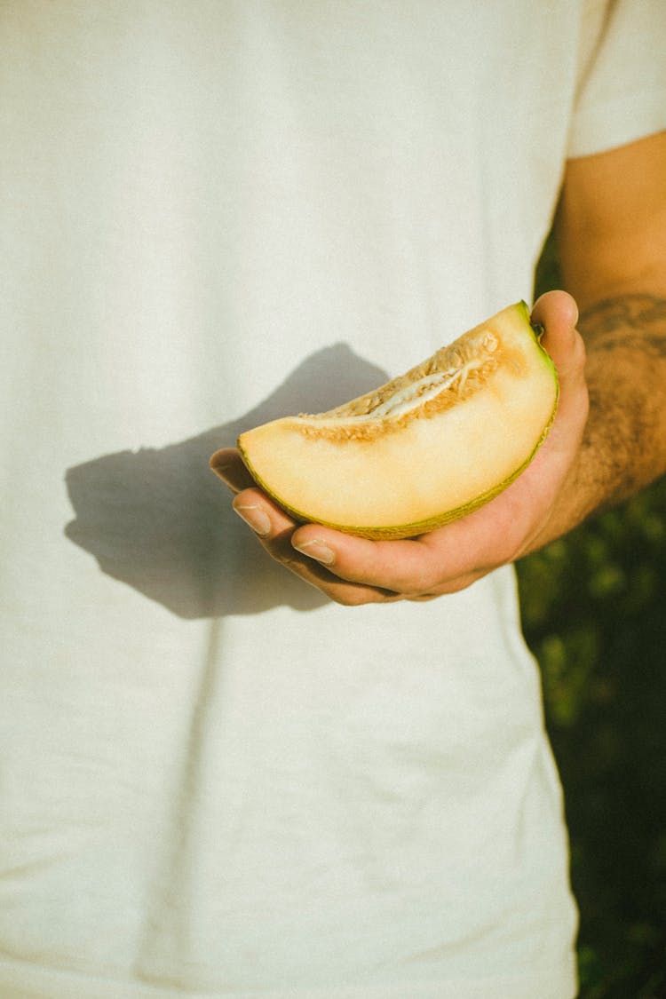 Unrecognizable Man Holding Piece Of Melon In Hand