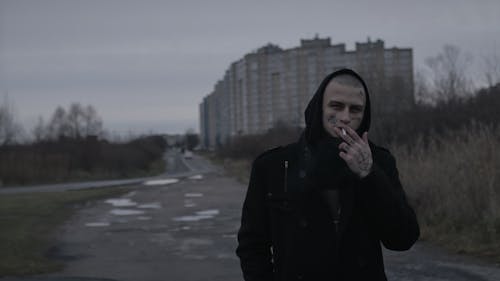A Man in Black Hoodie Jacket Smoking on the Street