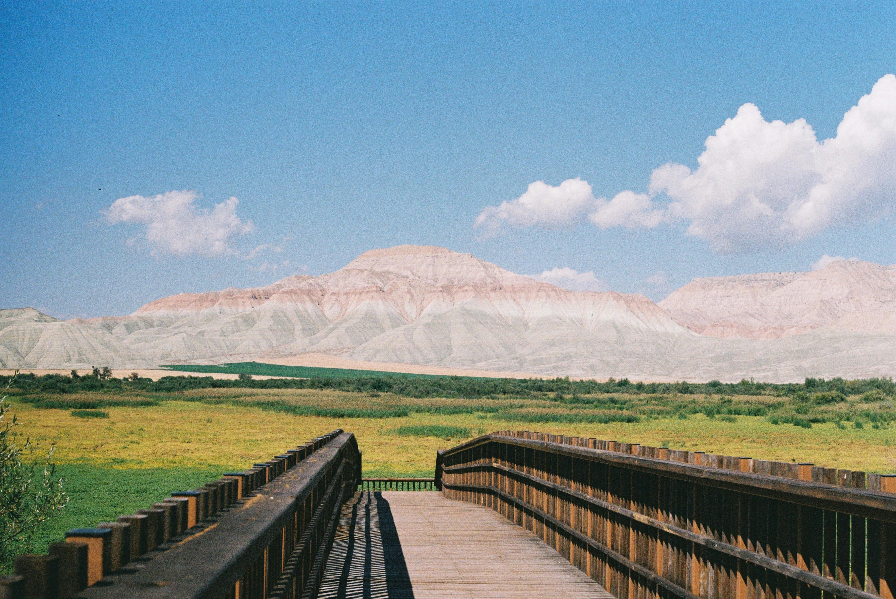 Explore a stunning view of Ankara, Turkey featuring a wooden walkway against distant mountains under a blue sky.