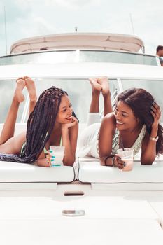 Two women enjoy a sunny day relaxing on a yacht in Dar es Salaam, Tanzania.