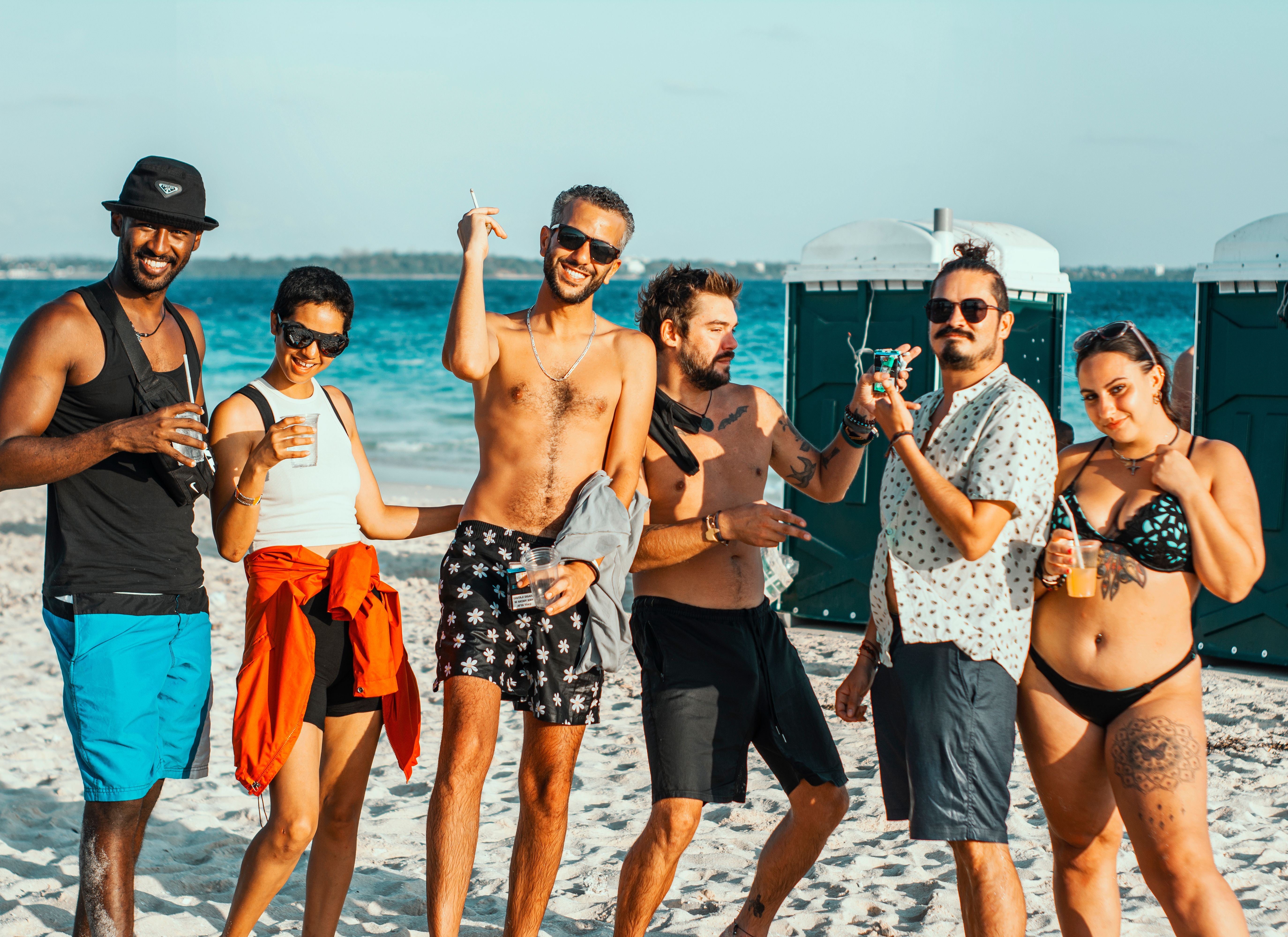 Groupe d'amis à la plage portant des tatouages temporaires visibles, ambiance fun et estivale
