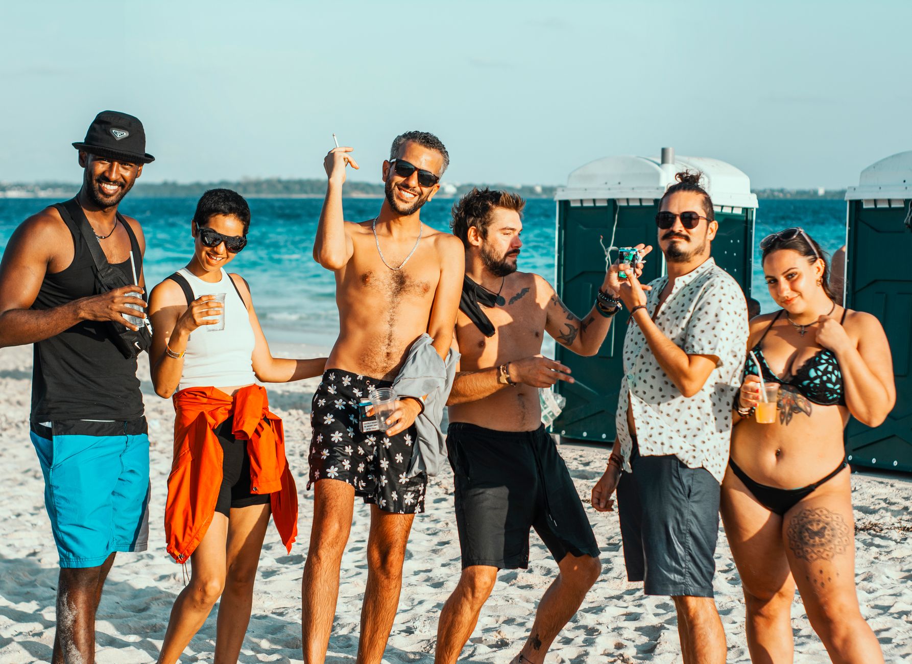Groupe d'amis à la plage portant des tatouages temporaires visibles, ambiance fun et estivale