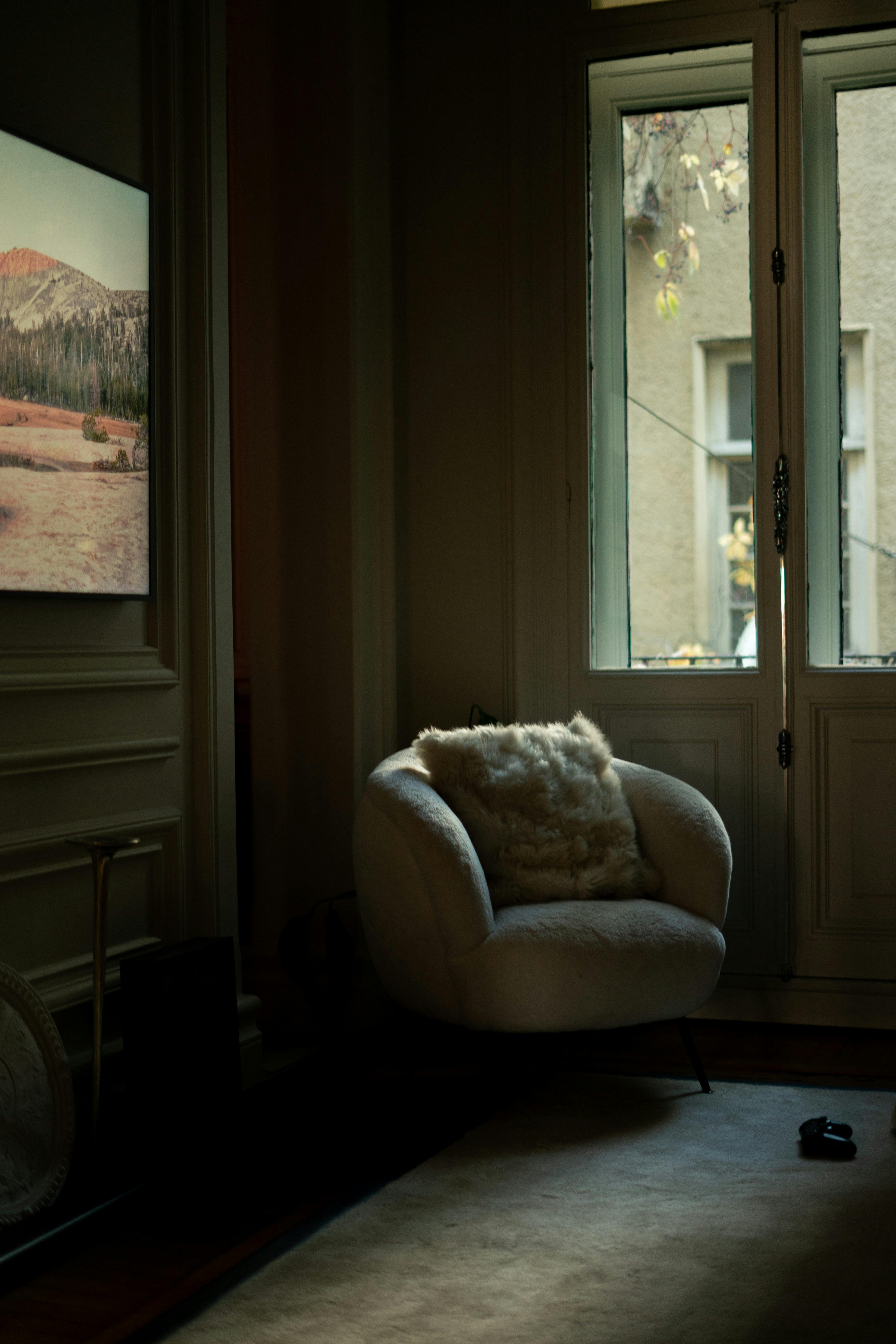A plush armchair by a door in a softly lit İstanbul interior, creating a warm, serene ambiance.
