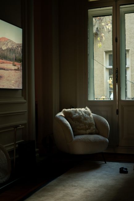 A plush armchair by a door in a softly lit İstanbul interior, creating a warm, serene ambiance.
