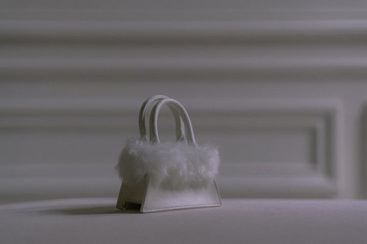 A White Small Bag With Fur On A White Surface