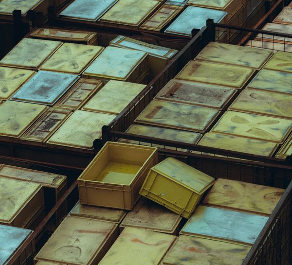 Overhead view of weathered yellow and green storage bins stacked in rows — Tony Mrst on Pexels