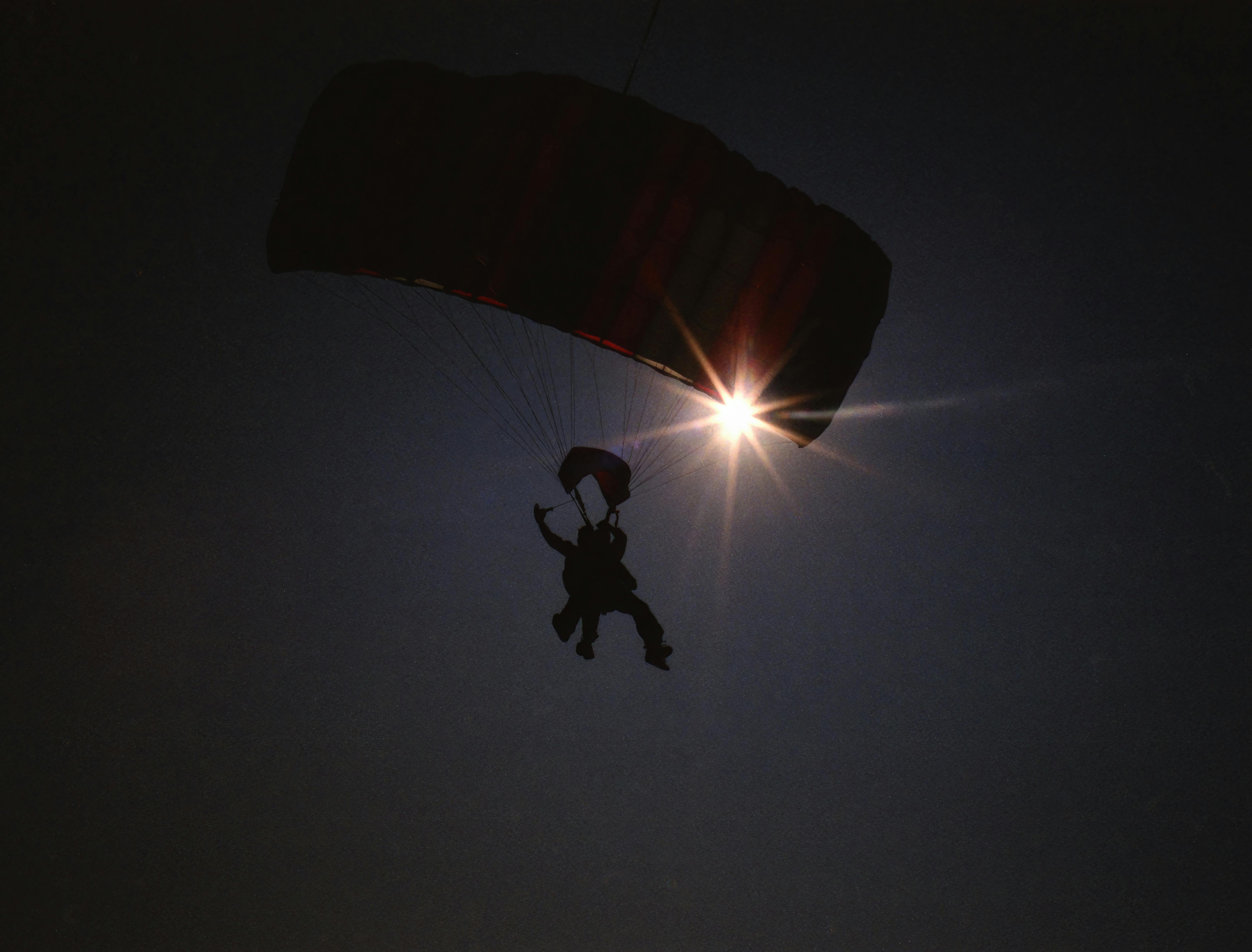 A dramatic silhouette of a paraglider in the sky with vibrant sunbeams in Baldwin, WI.