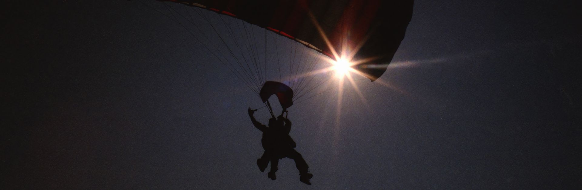A dramatic silhouette of a paraglider in the sky with vibrant sunbeams in Baldwin, WI.