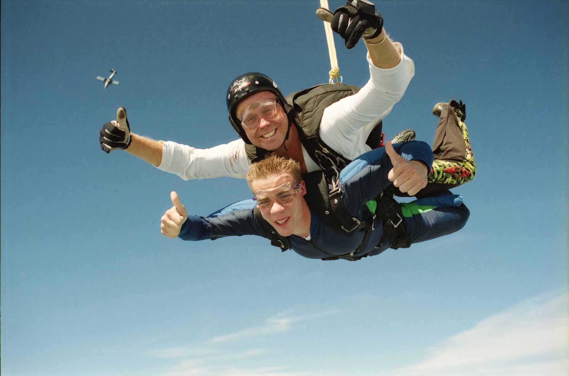 Skydivers enjoy an exhilarating tandem jump against a clear blue sky, showcasing adventure and thrill.