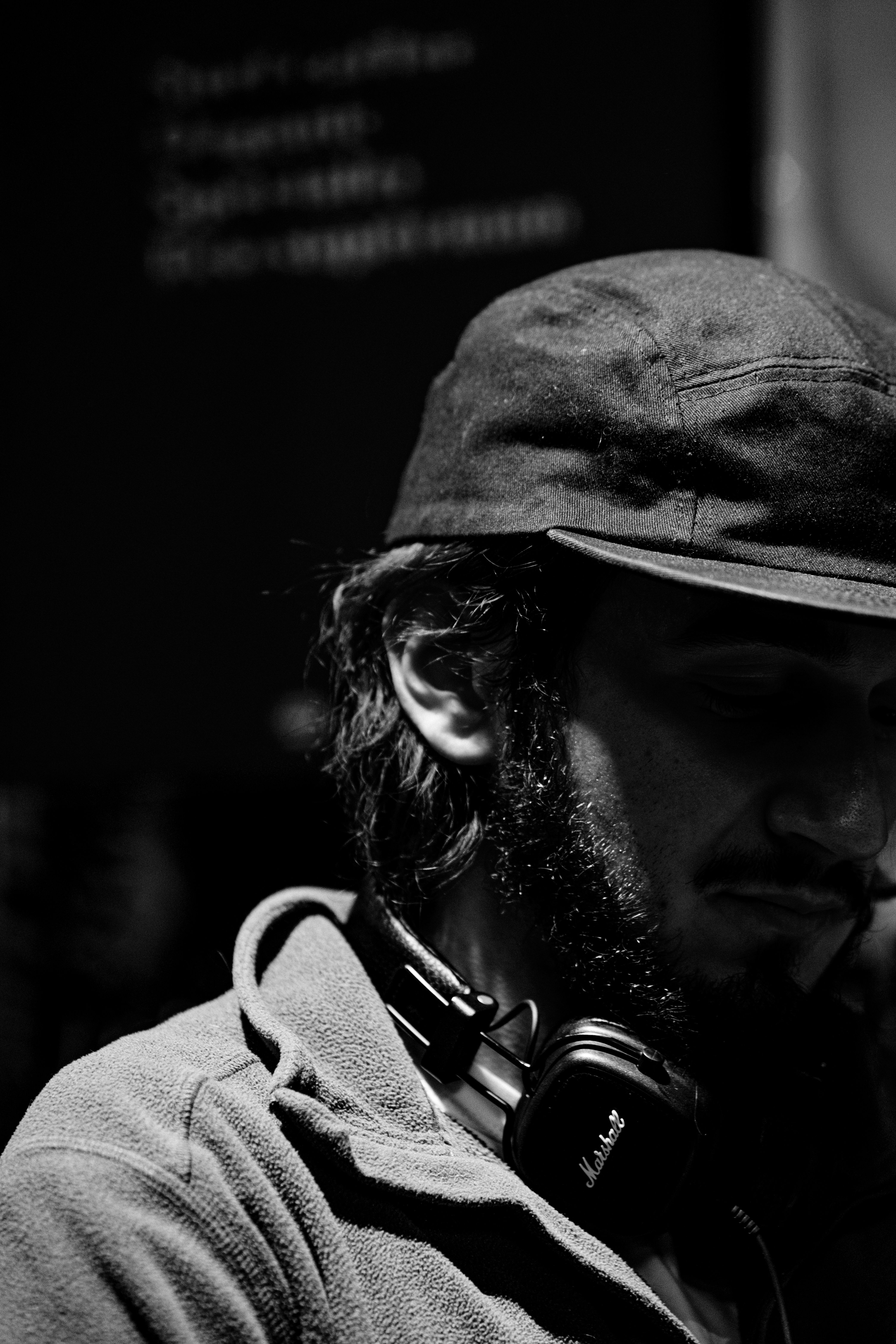 Black and white portrait of a man wearing a cap and headphones, with an obscured face.