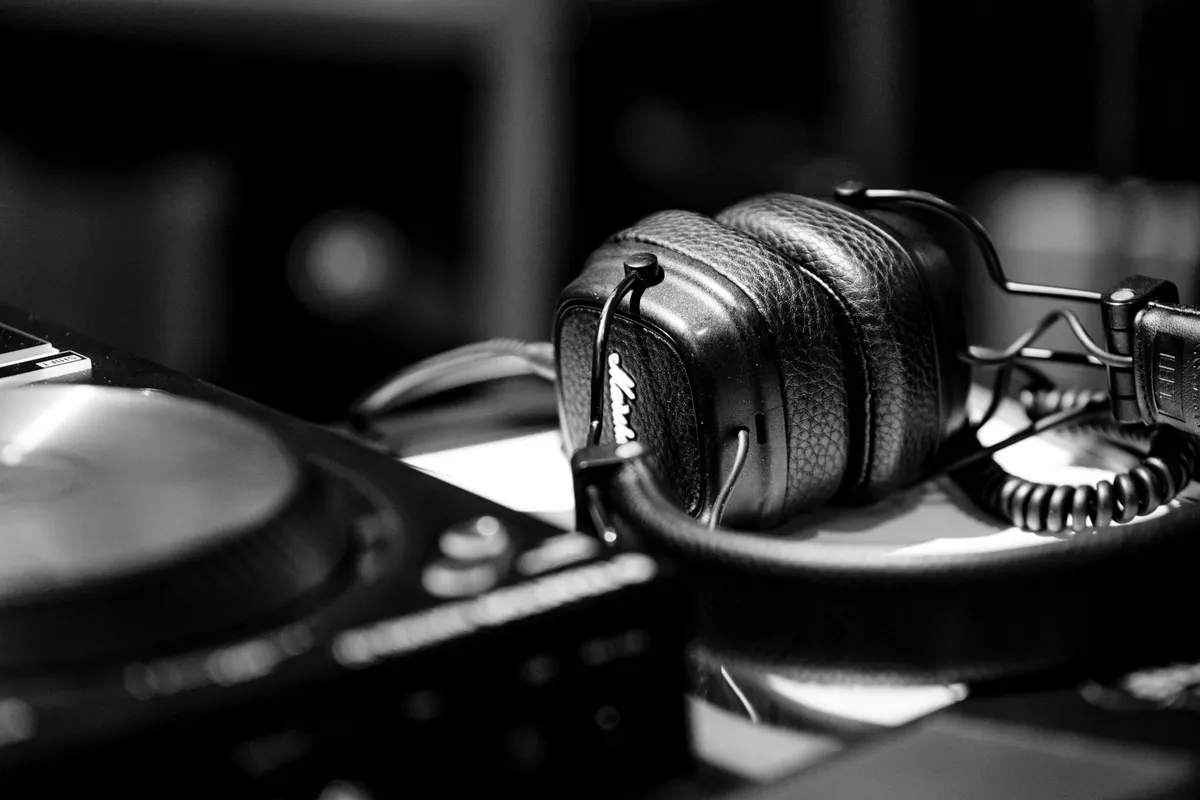 Tangan menjelajah daftar audio trending pada aplikasi musik streaming dengan headphone tergeletak di samping