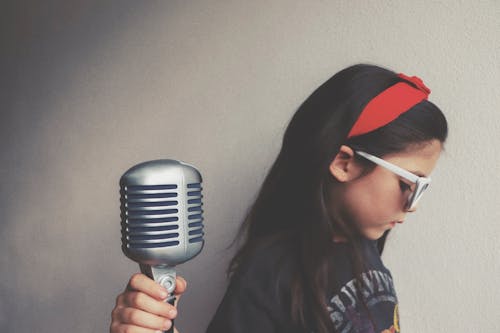 Young Girl Wearing Sunglasses Holding a Mic