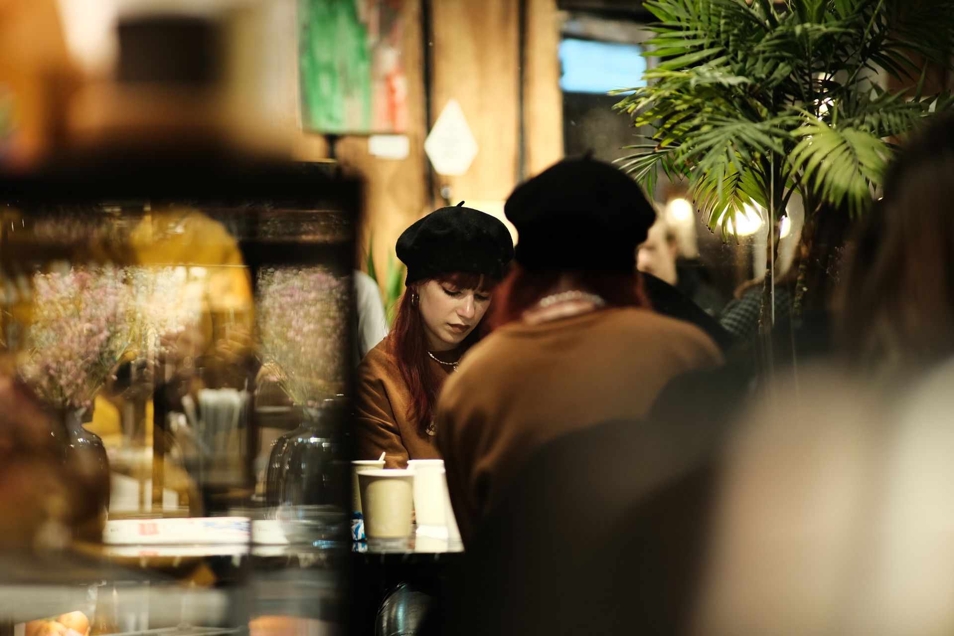 Warm, moody atmosphere in a cafe with a reflective setting and people seated.