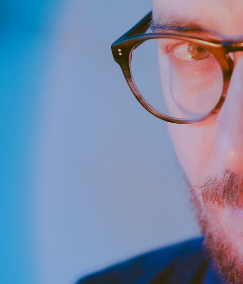 Free A close-up shot of a man wearing glasses against a blue background. Stock Photo