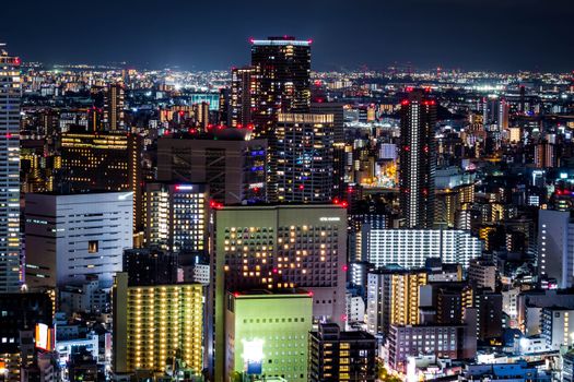 A dazzling view of Osaka's skyline at night featuring modern skyscrapers and glowing city lights.