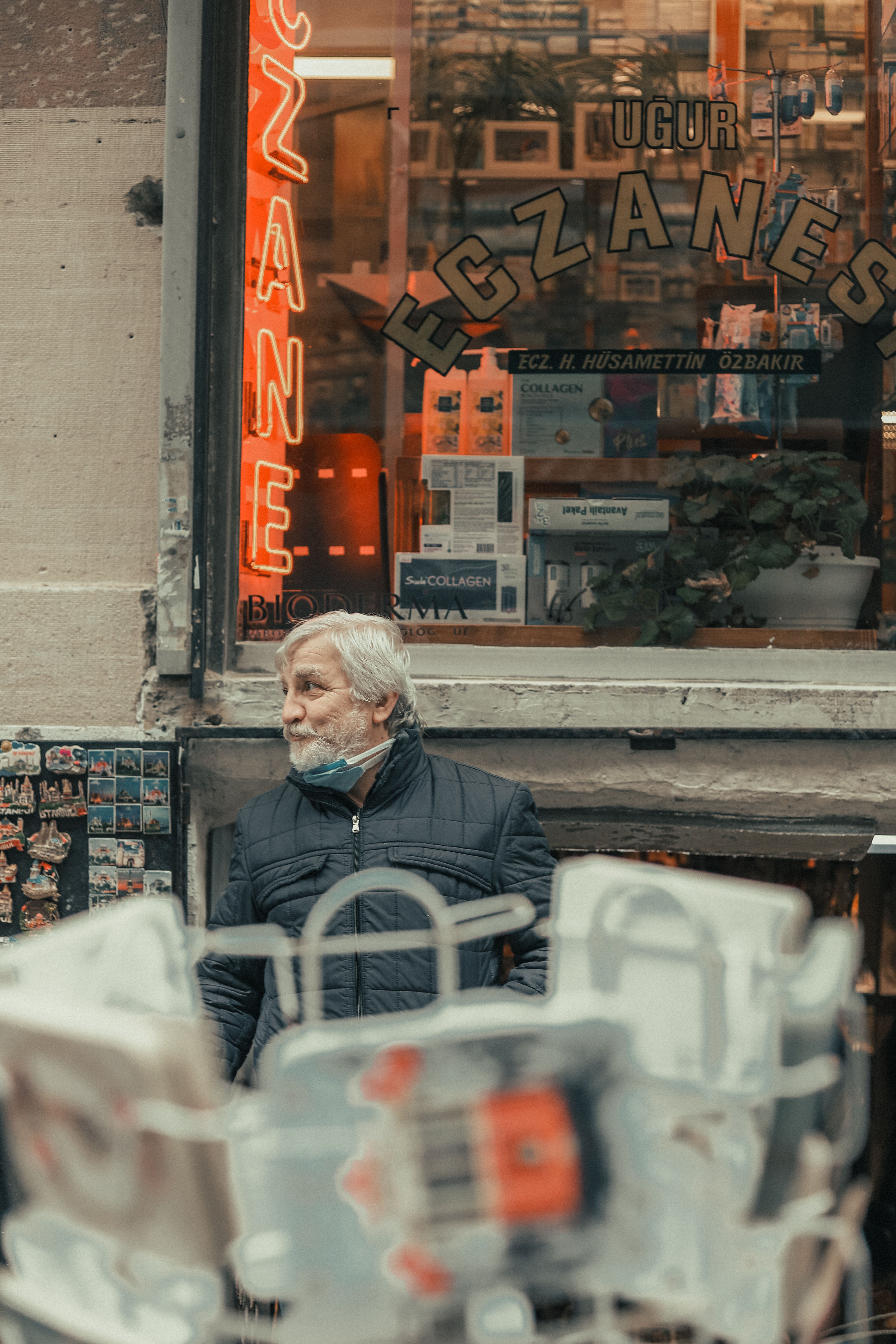 Senior man wearing mask outside Istanbul pharmacy, street view.