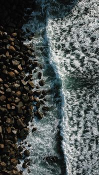 Stunning aerial shot of waves crashing on a rocky shoreline, showcasing nature's power.